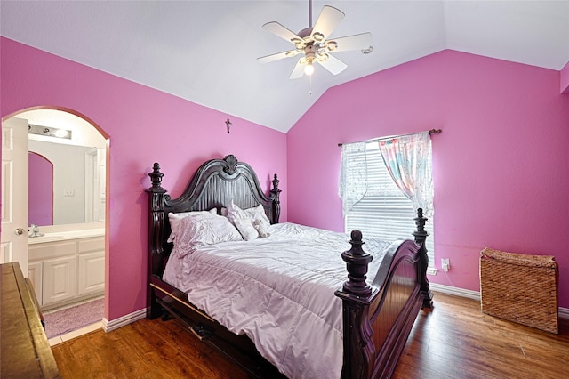 bedroom with lofted ceiling, arched walkways, baseboards, and wood finished floors