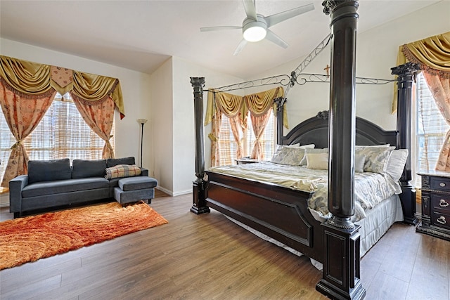 bedroom with lofted ceiling, multiple windows, a ceiling fan, and wood finished floors