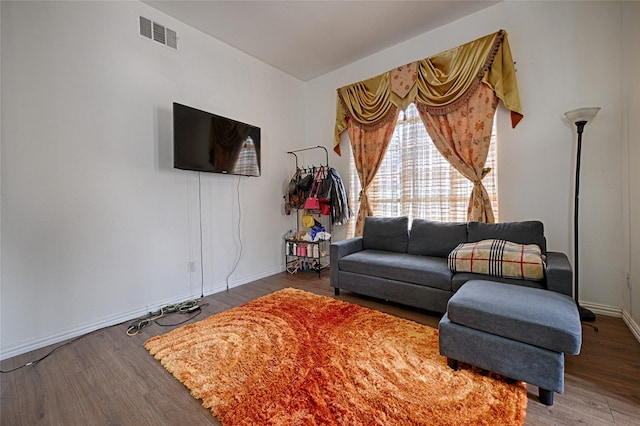 living area with wood finished floors, visible vents, and baseboards