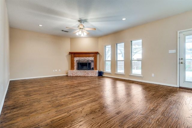 unfurnished living room with a fireplace, wood finished floors, visible vents, and a ceiling fan