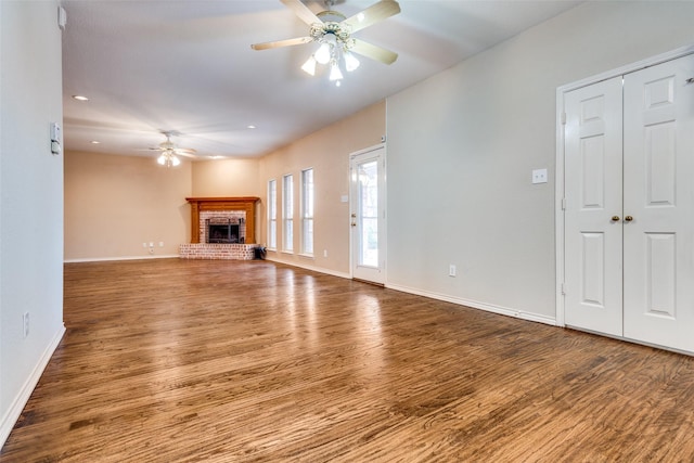 unfurnished living room featuring a fireplace, wood finished floors, a ceiling fan, and baseboards