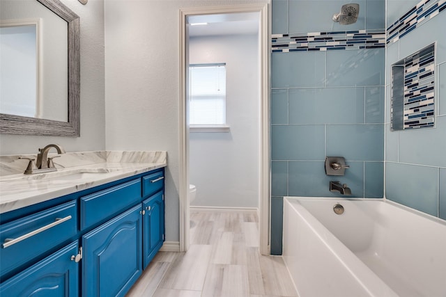 bathroom featuring shower / bath combination, baseboards, toilet, wood finished floors, and vanity