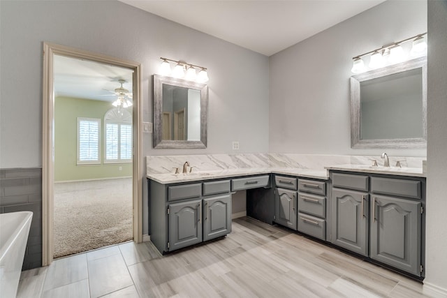 full bath featuring double vanity, a sink, a bathtub, and a ceiling fan