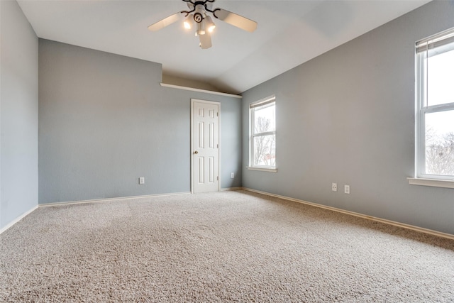 empty room with ceiling fan, vaulted ceiling, carpet, and baseboards