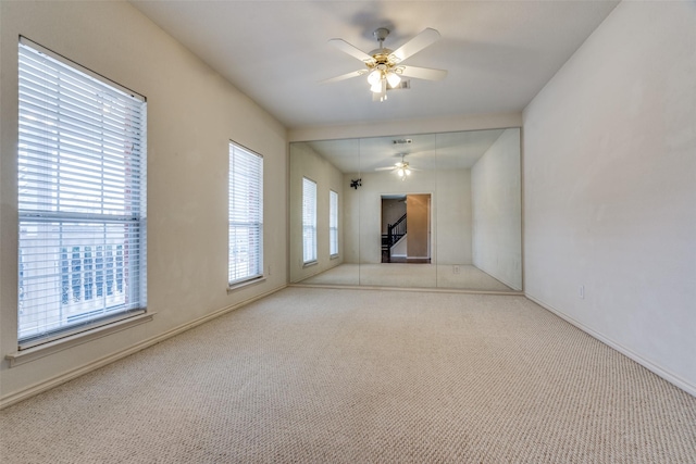 unfurnished living room with carpet, baseboards, and ceiling fan