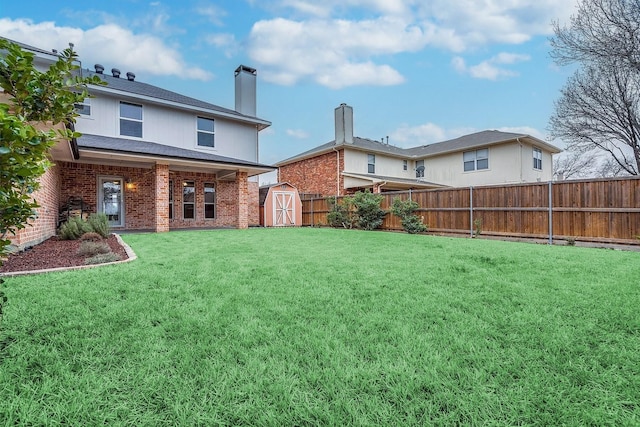 back of house featuring a chimney, a storage shed, a lawn, brick siding, and a fenced backyard