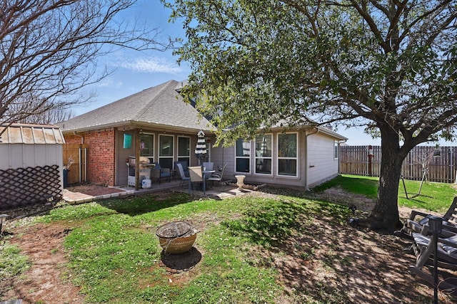 back of house with an outbuilding, a patio, fence, a fire pit, and brick siding