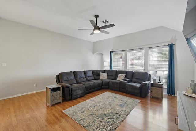 living area with visible vents, baseboards, ceiling fan, light wood-type flooring, and arched walkways