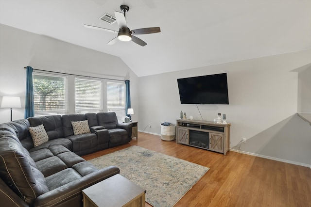 living area featuring light wood finished floors, visible vents, baseboards, and vaulted ceiling