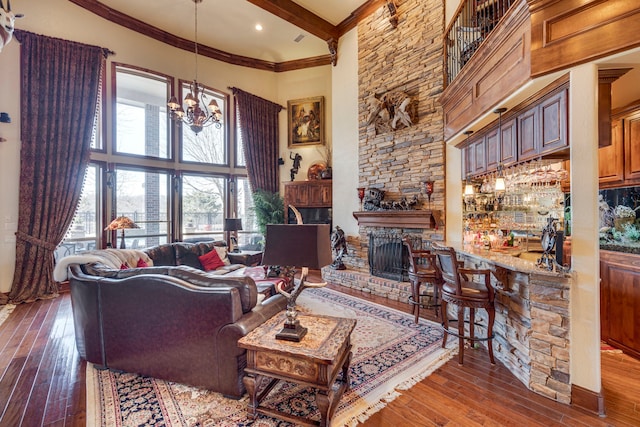 living area featuring a high ceiling, a fireplace, beam ceiling, hardwood / wood-style floors, and an inviting chandelier