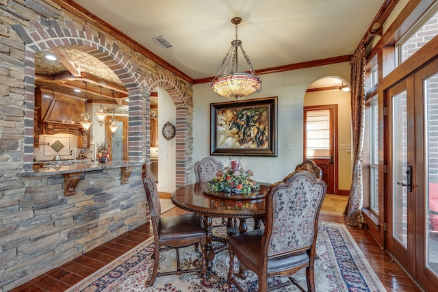 dining room with visible vents, arched walkways, ornamental molding, wood finished floors, and french doors