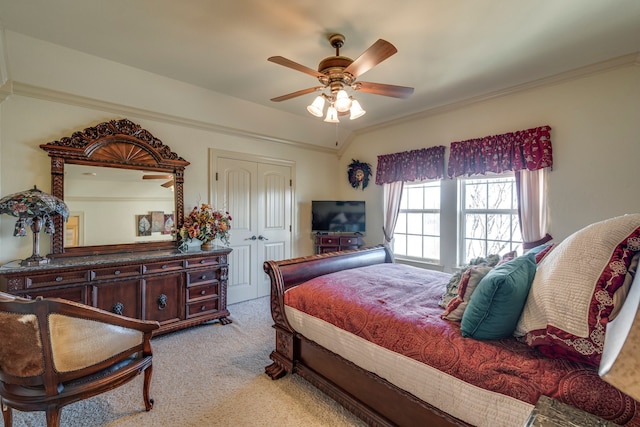 bedroom with a ceiling fan, ornamental molding, a closet, and light colored carpet