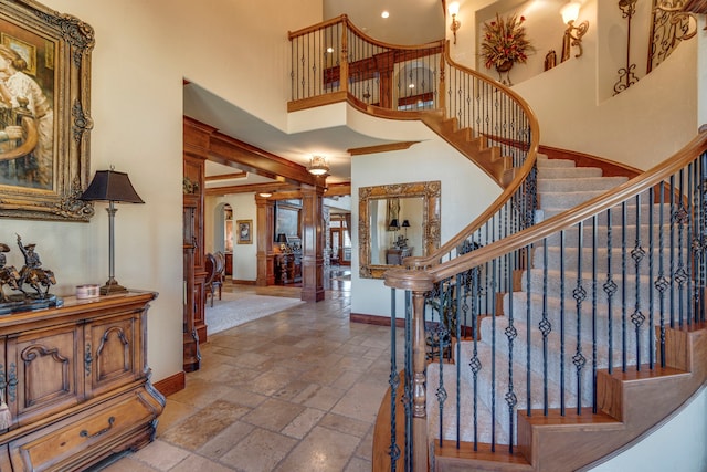 staircase with a high ceiling, stone tile flooring, and baseboards