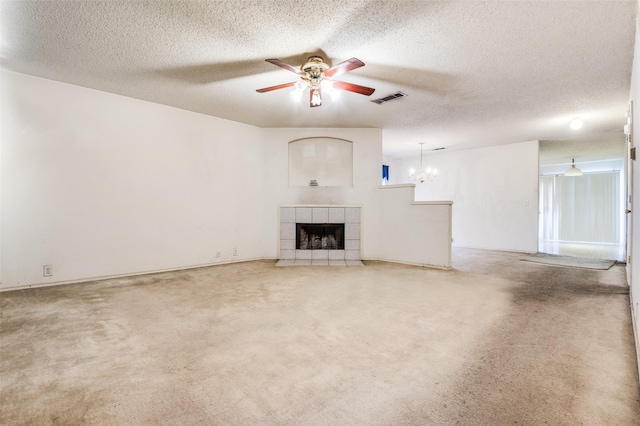 unfurnished living room featuring carpet floors, visible vents, a ceiling fan, a textured ceiling, and a tile fireplace