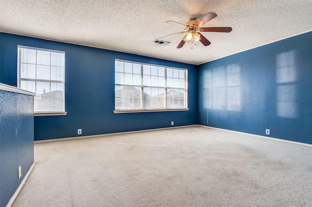 spare room with a ceiling fan, carpet, visible vents, and a healthy amount of sunlight