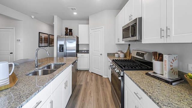 kitchen featuring light wood-style flooring, stainless steel appliances, a sink, visible vents, and white cabinetry