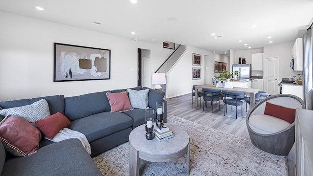 living area featuring light wood-type flooring, visible vents, stairway, and recessed lighting