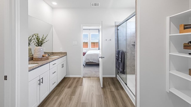 bathroom featuring ensuite bathroom, wood finished floors, a sink, visible vents, and a stall shower