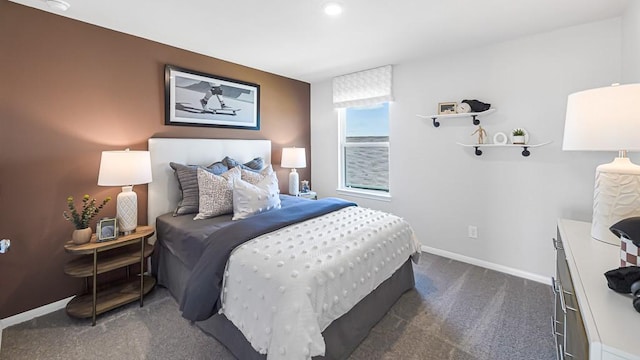 bedroom with dark colored carpet and baseboards