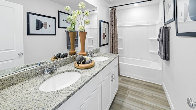 bathroom with wood finish floors, double vanity, a sink, and shower / bath combo