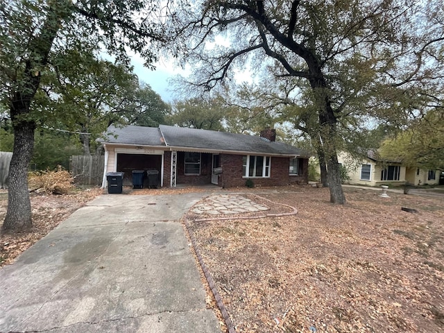 ranch-style home with a garage, brick siding, fence, driveway, and a chimney