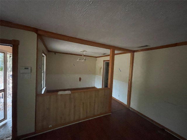 empty room featuring visible vents, crown molding, and a textured ceiling