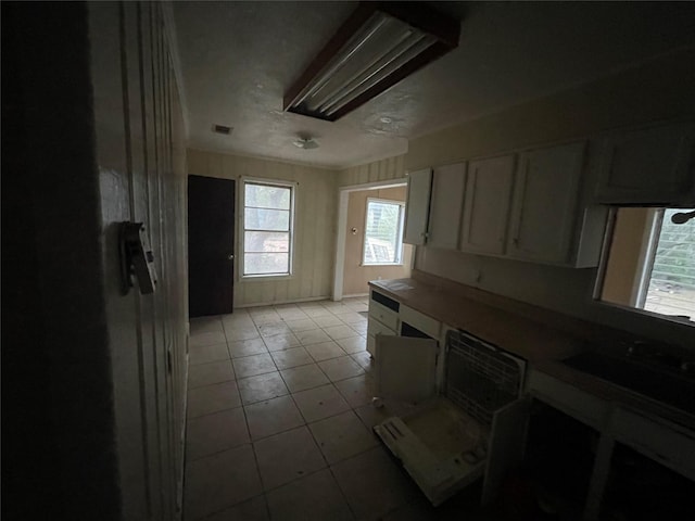 kitchen featuring light tile patterned floors, visible vents, and white cabinetry