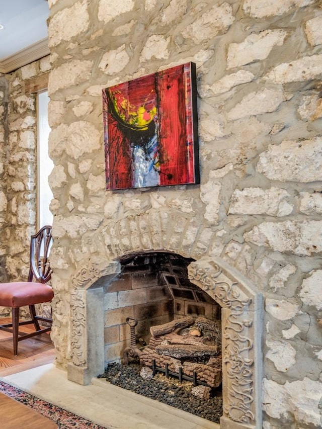 room details featuring crown molding, a fireplace, and wood finished floors