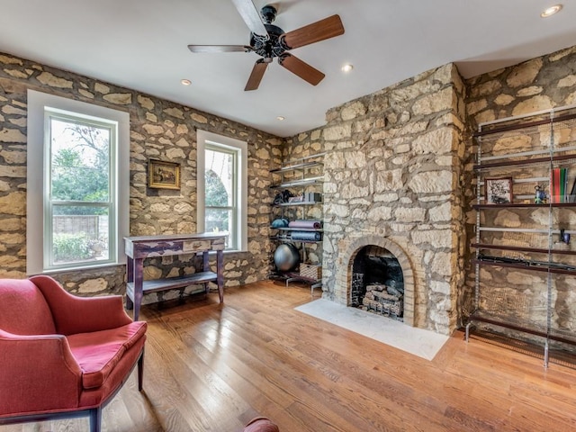 living room featuring a healthy amount of sunlight, a fireplace, a ceiling fan, and wood finished floors