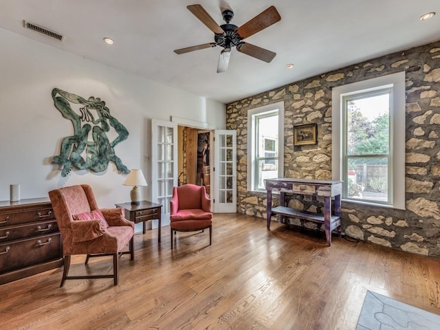 sitting room featuring a ceiling fan, visible vents, and wood finished floors