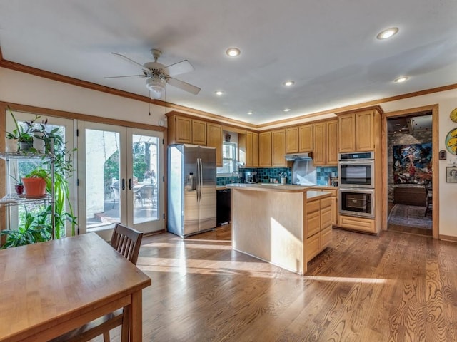 kitchen with under cabinet range hood, stainless steel appliances, french doors, a center island, and light wood finished floors