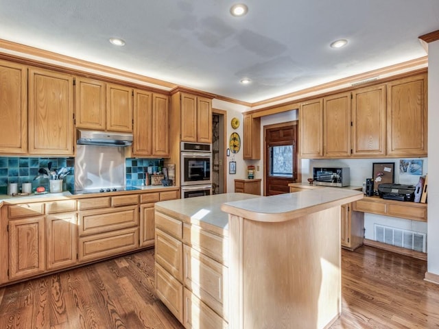 kitchen featuring a center island, light countertops, visible vents, wood finished floors, and under cabinet range hood