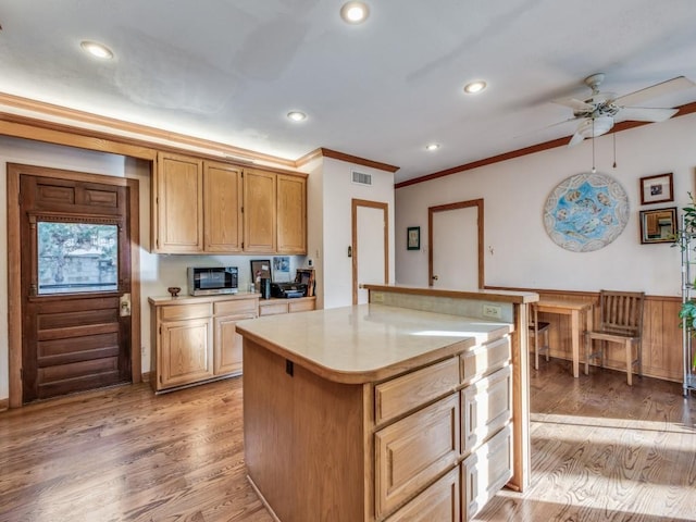 kitchen featuring light wood finished floors, visible vents, stainless steel microwave, and light countertops