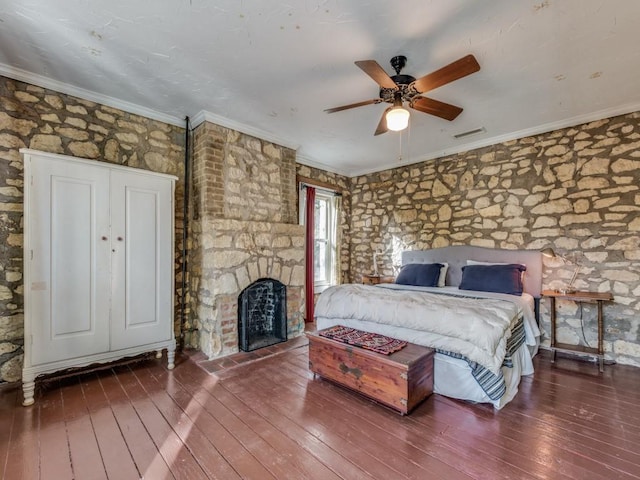 bedroom with wood-type flooring, a fireplace, visible vents, and crown molding