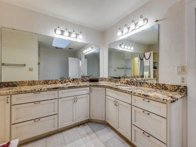 full bathroom with a skylight, tile patterned flooring, a sink, and double vanity