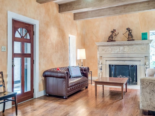 sitting room featuring beam ceiling, a fireplace, baseboards, and wood finished floors