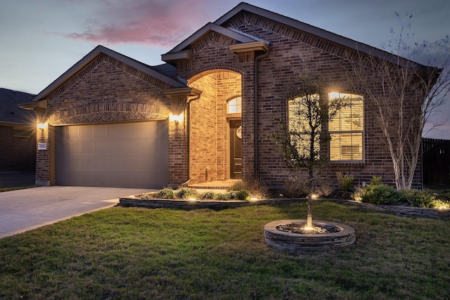 french country home featuring a yard, concrete driveway, brick siding, and an attached garage