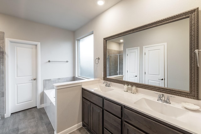 full bathroom featuring a stall shower, double vanity, a sink, and a bath