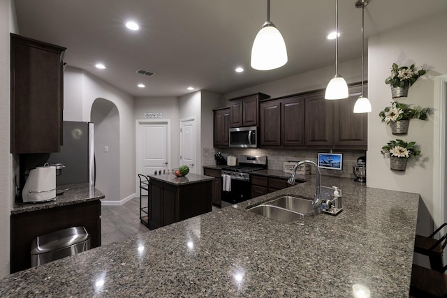 kitchen featuring a breakfast bar, stainless steel appliances, visible vents, a sink, and dark brown cabinets