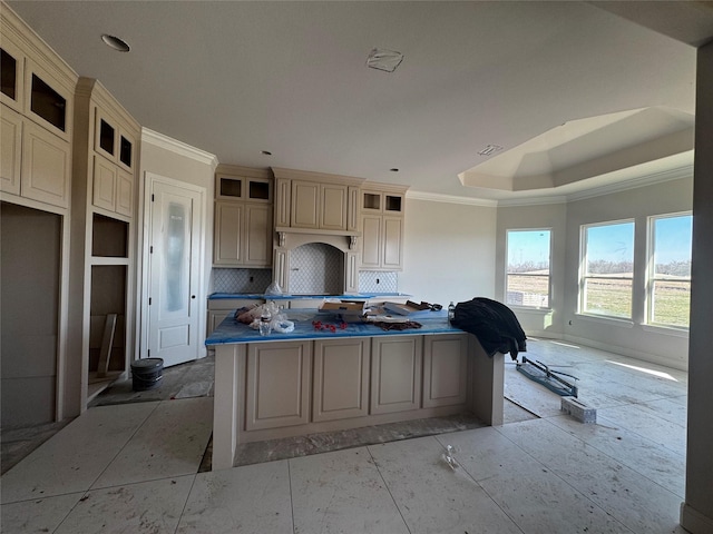 kitchen featuring a kitchen island, a tray ceiling, crown molding, cream cabinetry, and backsplash