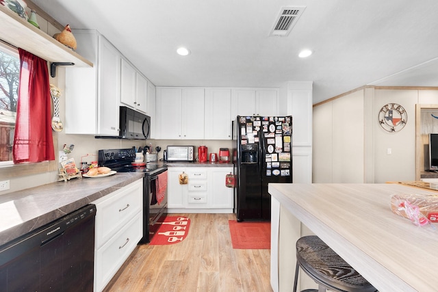 kitchen with recessed lighting, visible vents, white cabinets, black appliances, and light wood finished floors