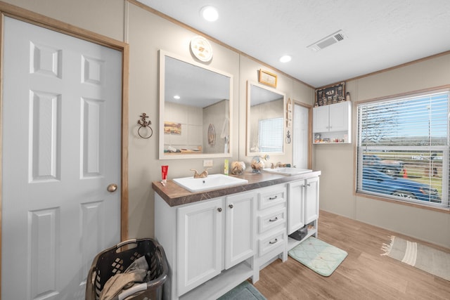 full bathroom with double vanity, wood finished floors, a sink, and visible vents