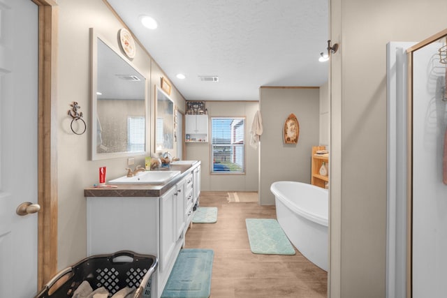 full bathroom with a stall shower, a soaking tub, wood finished floors, a textured ceiling, and vanity