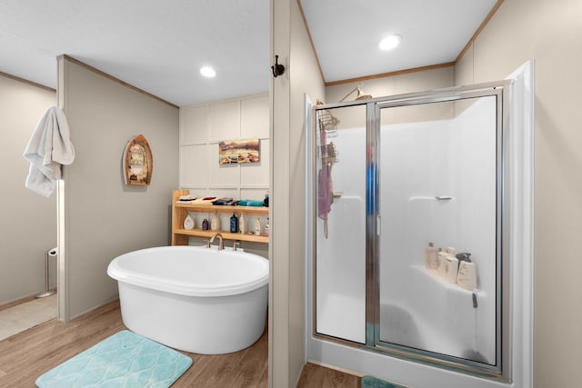 bathroom with recessed lighting, wood finished floors, a freestanding bath, a shower stall, and crown molding