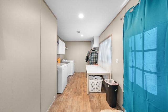 clothes washing area featuring light wood-style floors, visible vents, cabinet space, and washing machine and clothes dryer