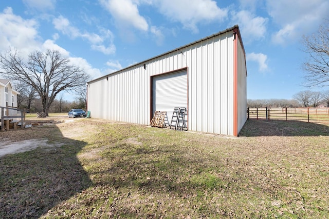 view of outbuilding with an outbuilding, fence, and driveway