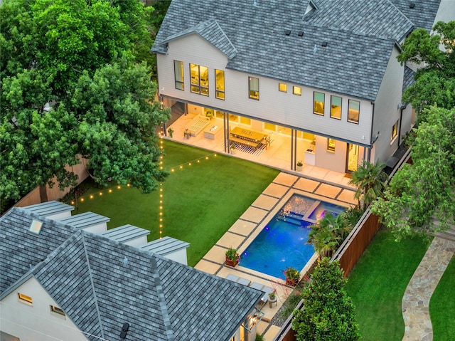 back of house with a fenced backyard, a jacuzzi, a patio, and a yard