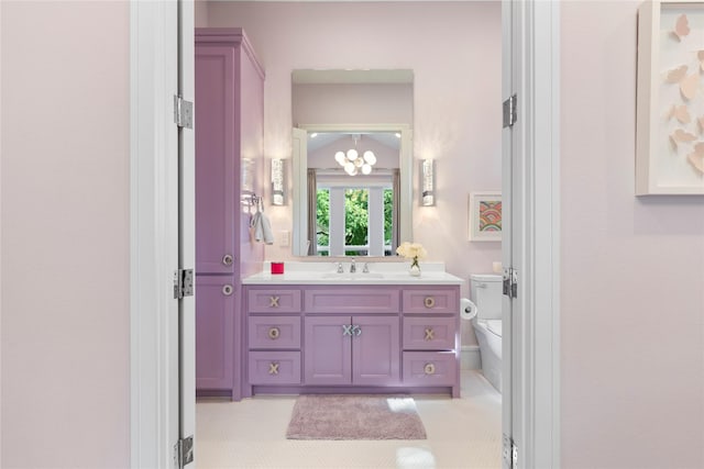 bathroom with toilet, a notable chandelier, and vanity