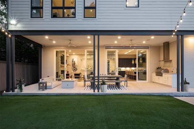 back of property with a patio, an outdoor kitchen, fence, a ceiling fan, and a yard