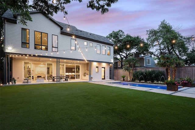 rear view of property with a fenced in pool, fence, a patio, and a lawn